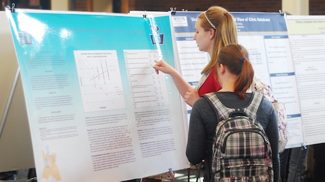 A student explains her research to another student.